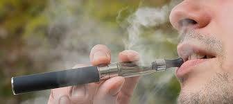 一個人吸入黑色和銀色電子香煙蒸氣時的嘴部特寫，臉部周圍可見可見的煙霧。. 電子煙 vape